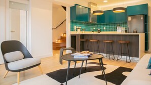 A modern kitchen with teal cabinets, a bar area with stools, and a dining table with a book. - w Inviting 3BR w Balcony in Hip Miraflores (Lima)