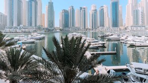 A marina with multiple yachts docked, surrounded by high-rise buildings and palm trees. - Luxury 1BR in Dubai Marina Beside Vida Yacht Club (Dubai)