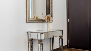 A rustic wooden console table with a glass top, positioned against a white wall with a large mirror above it. - Luxury 1BR in Dubai Marina Beside Vida Yacht Club (Dubai)