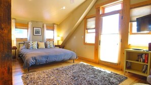 A bedroom with a bed, a ceiling fan, a bookshelf, and a large window. - Townhome in Crested Butte | 2 Bedroom | Walk to Elk Ave | Parking (Crested Butte)