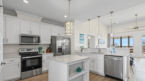 A modern kitchen with white cabinetry, stainless steel appliances, and a central island.