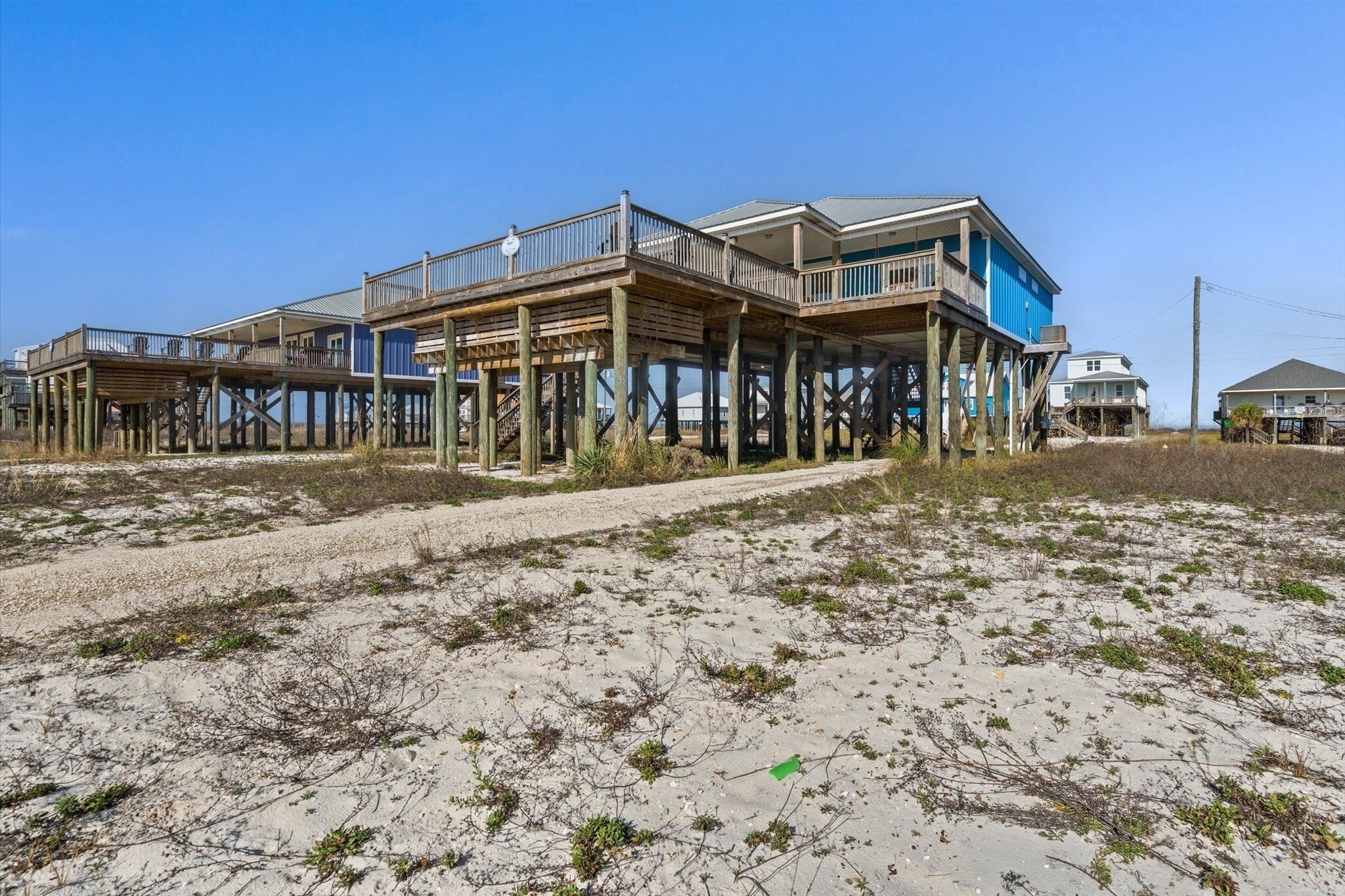 Une maison située en bord de mer, dotée de plusieurs terrasses et donnant sur une plage de sable.