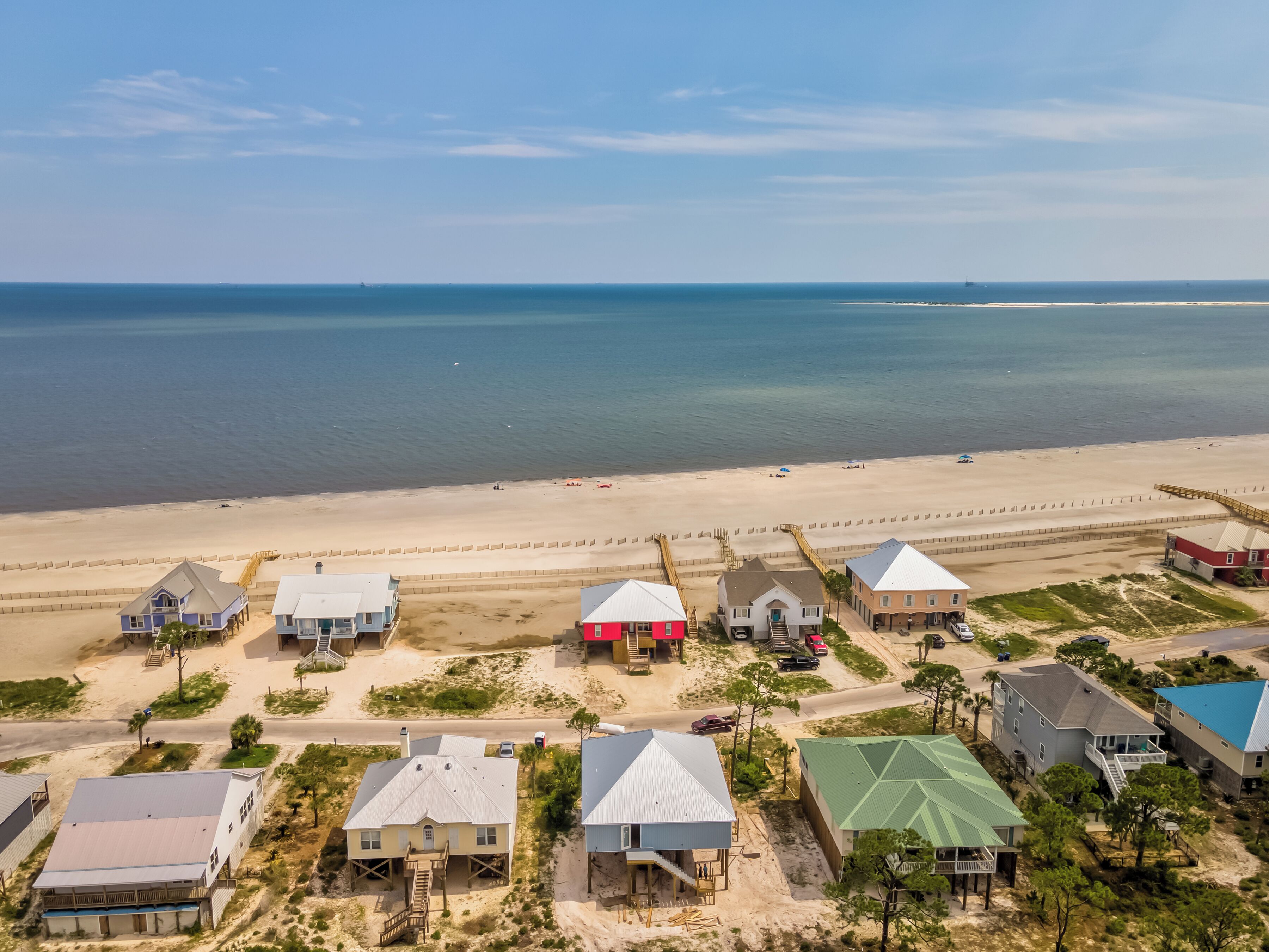 Un quartier résidentiel situé sur la côte, avec des maisons, une plage et une vue dégagée sur l’océan.