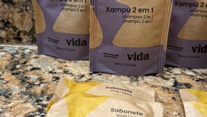 Three shampoo and soap packages labeled 'Xampu 2 em 1' and 'vida' on a granite countertop. - Go Hotelaria (Búzios)