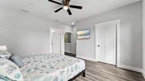 Quarto com uma cama, ventilador de teto e um quadro na parede.