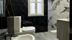 A modern bathroom with a freestanding bathtub, a toilet, and a vanity with a mirror.