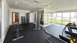 Una palestra moderna con diverse attrezzature per l'allenamento, ampie finestre e un ambiente pulito e spazioso.