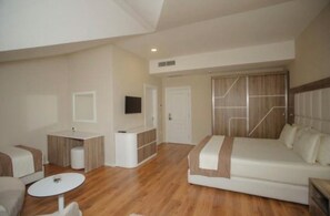 A modern hotel room with a bed, a small table, a sofa, and a TV. - Kompleksi Exalco-Al (Bushat)