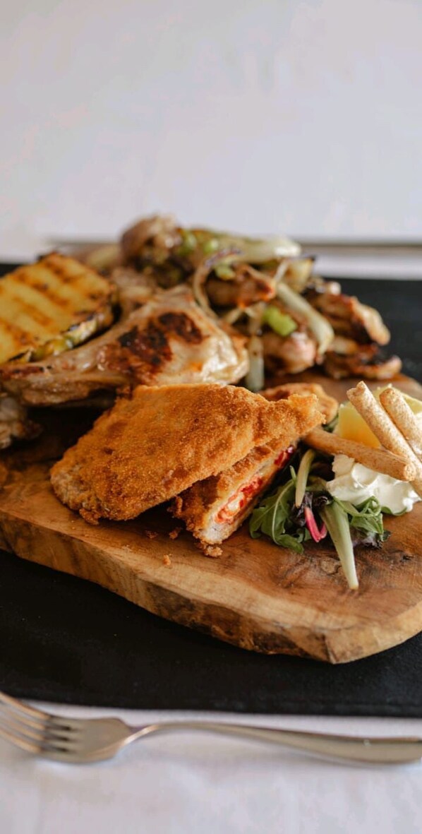 A wooden board with a grilled sandwich and a side of vegetables. - Kompleksi Exalco-Al (Bushat)
