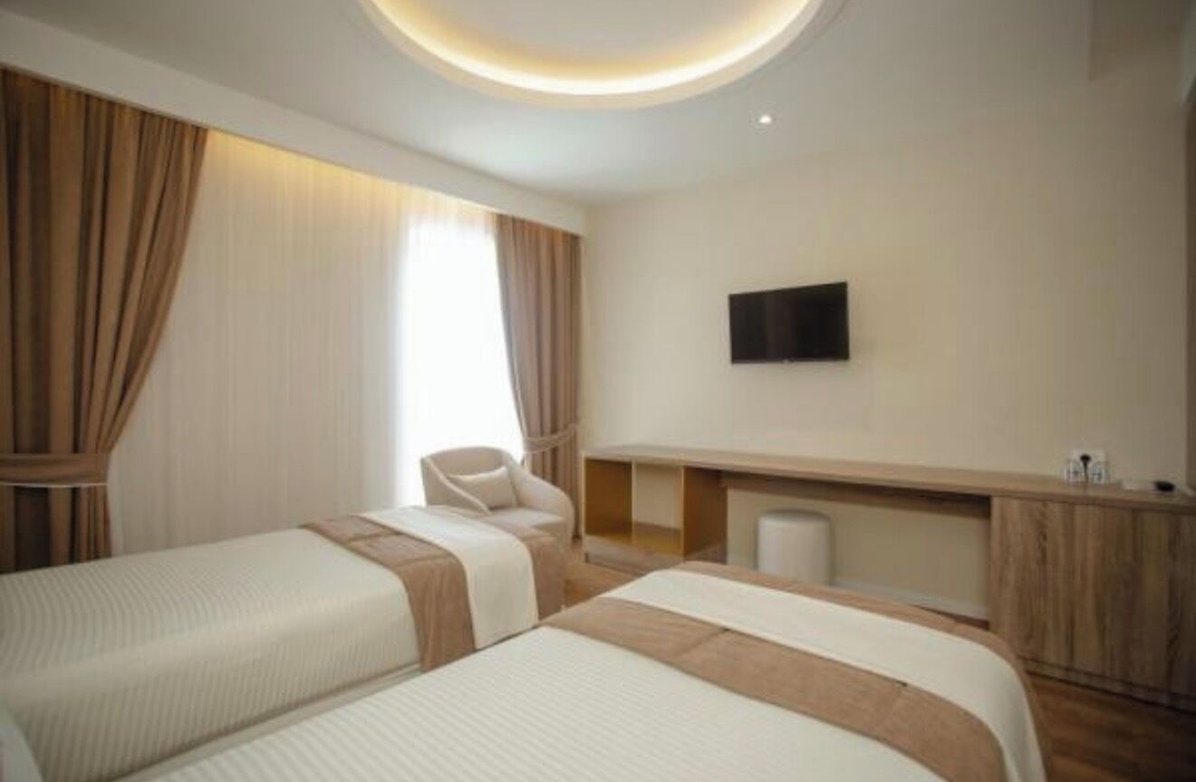 Ein Hotelzimmer mit zwei Betten, einem Flachbildfernseher, einem Schreibtisch und einem Stuhl.
