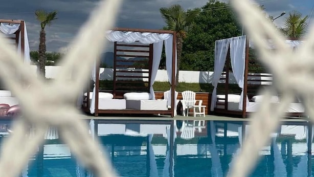 Area piscina con tende bianche e poltrone relax.