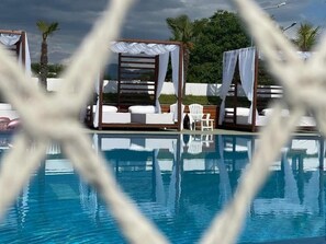 Un área de piscina con toldos blancos y sillas de descanso.