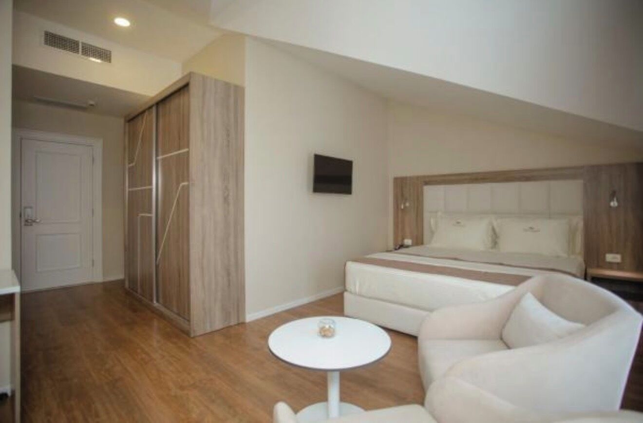 A bedroom with a bed, a sofa, a small round table, and a wardrobe.