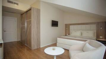 A bedroom with a bed, a sofa, a small round table, and a wardrobe.