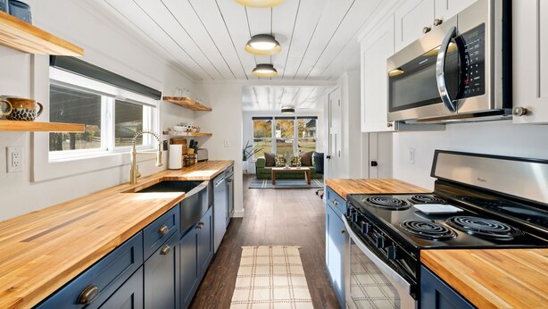 Een moderne keuken met houten aanrecht, een rvs fornuis en een magnetron.