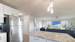 A modern kitchen with a stainless steel refrigerator, white cabinets, and a granite countertop. - Beach Boyd's by Liquid Life (Gulf Shores)
