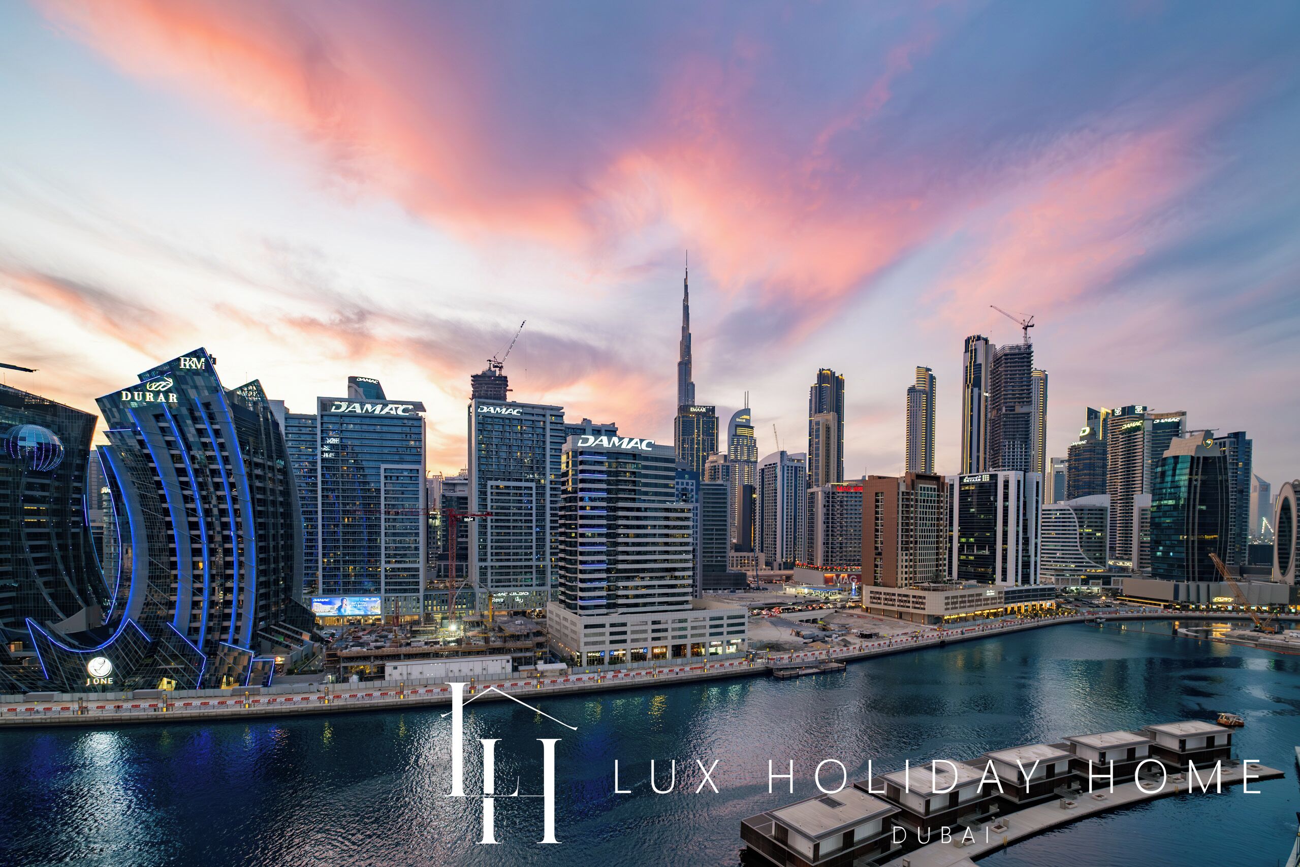 Un paysage urbain avec des immeubles modernes de grande hauteur, dont le Burj Khalifa, et une zone riveraine dotée d’un port de plaisance.