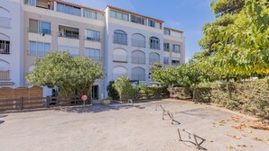 A multi-story residential building with balconies, a gated entrance, and a clear sky. - Cosy Apartment Near Sandy Beach (Agde)