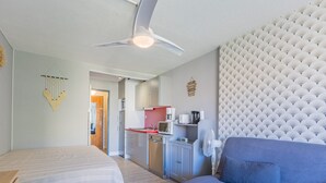 A bedroom with a bed, a sofa, a ceiling fan, a kitchenette, and a bathroom. - Cosy Apartment Near Sandy Beach (Agde)