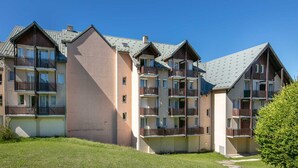 A multi-story residential building with balconies, a flat roof, and a grassy courtyard. - Mountain Apartment Near Village Centre (Villard-de-Lans)