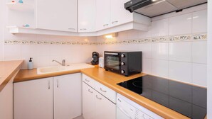 A modern kitchen with white cabinets, a wooden countertop, a black microwave, a coffee maker, and a dishwasher. - Le Repos Marin (Valras-Plage)