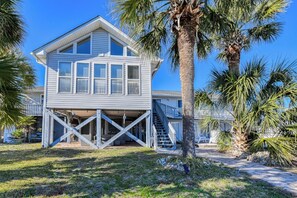 A two-story house with a balcony, a staircase, and a palm tree in the foreground. - Five Bedroom Home with a Private Pool on the Channel and Pet Friendly (Garden City Beach)