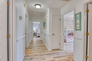 A hallway with wooden flooring, white walls, and doors leading to bedrooms. - Five Bedroom Home with a Private Pool on the Channel and Pet Friendly (Garden City Beach)