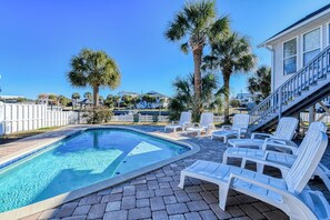 A swimming pool with clear water, surrounded by white lounge chairs and palm trees. - Five Bedroom Home with a Private Pool on the Channel and Pet Friendly (Garden City Beach)