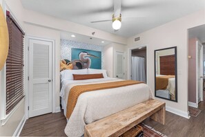 Ein Schlafzimmer mit einem Bett, einer Holzbank, einem Deckenventilator und einem Bild an der Wand.