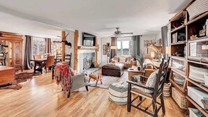 A spacious living room with a fireplace, wooden furniture, and a bookshelf.