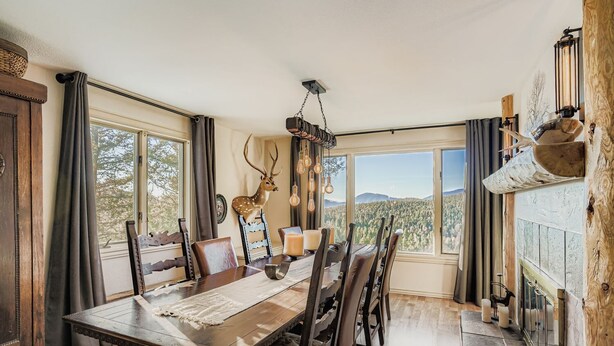 A dining area with a large table, chairs, a chandelier, and a deer head decoration.