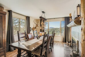 A dining area with a large table, chairs, a chandelier, and a deer head decoration. - Mountain Haven-Hot Tub+Pikes Peak+Red Rocks+Serene (Conifer)
