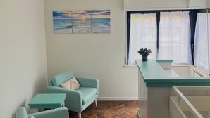 A compact living space with a kitchenette, a dining area with a teal sofa, and a herringbone wood floor. - B&B Lary (Pescara)