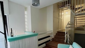 A modern kitchen with a herringbone wood floor, a central island with a white and teal countertop, and a staircase leading to an upper level. - B&B Lary (Pescara)