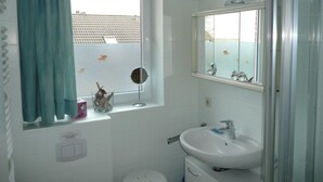 Een badkamer met raam, wastafel, spiegel en toilet.