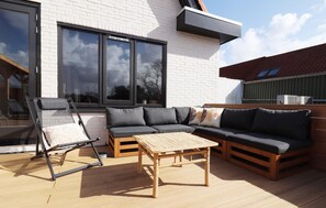 A modern outdoor living area with a sofa, a wooden table, and a lounge chair.