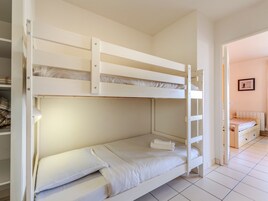A bunk bed room with a ladder, a small bedside table, and a framed picture on the wall.