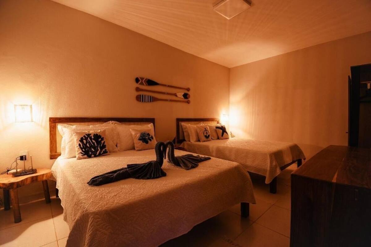 Ein Hotelzimmer mit zwei Betten, jeweils mit Kopfteil, Nachttischen und Lampen.