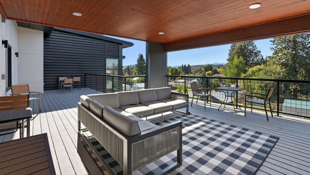 A spacious outdoor deck with a checkered floor, a sofa, and a table. - Near CDA Lake | Gym, In-Unit Laundry, Free Parking (Coeur d`Alene)