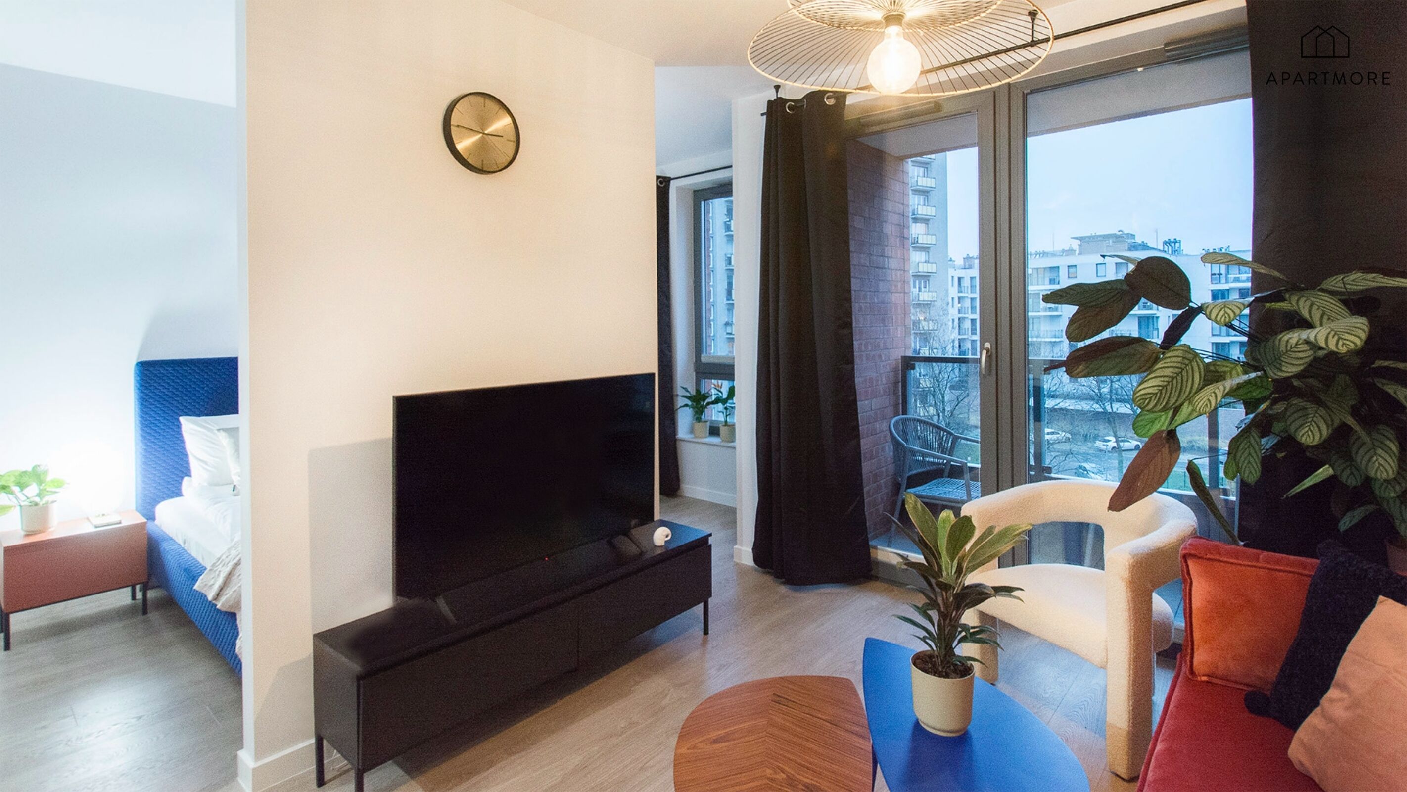 A modern living room with a flat-screen TV, a sofa, a coffee table, and a potted plant.
