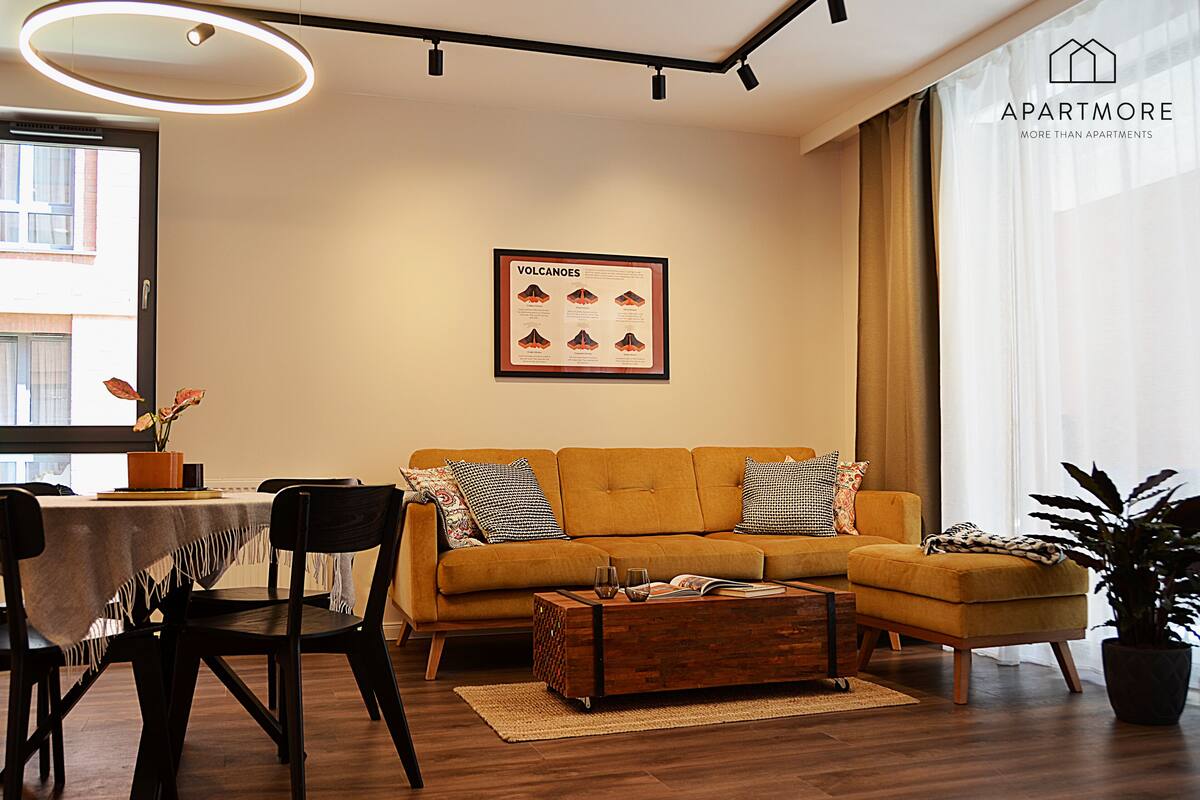 A modern living room with a sofa, coffee table, and a framed poster on the wall.