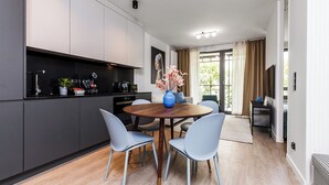 A modern kitchen with dark cabinets, a round wooden table, and light blue chairs. - City Center - Łąkowa street by Apartmore (Gdańsk)