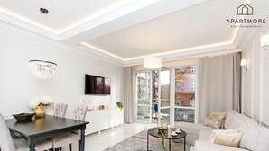 A modern living room with a dining area, a sofa, a TV, and a chandelier. - City Center - Łąkowa street by Apartmore (Gdańsk)
