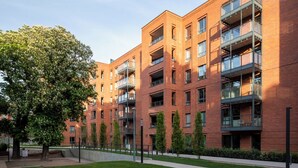 A modern multi-story building with brick exterior, balconies, and a well-maintained lawn. - City Center - Łąkowa street by Apartmore (Gdańsk)