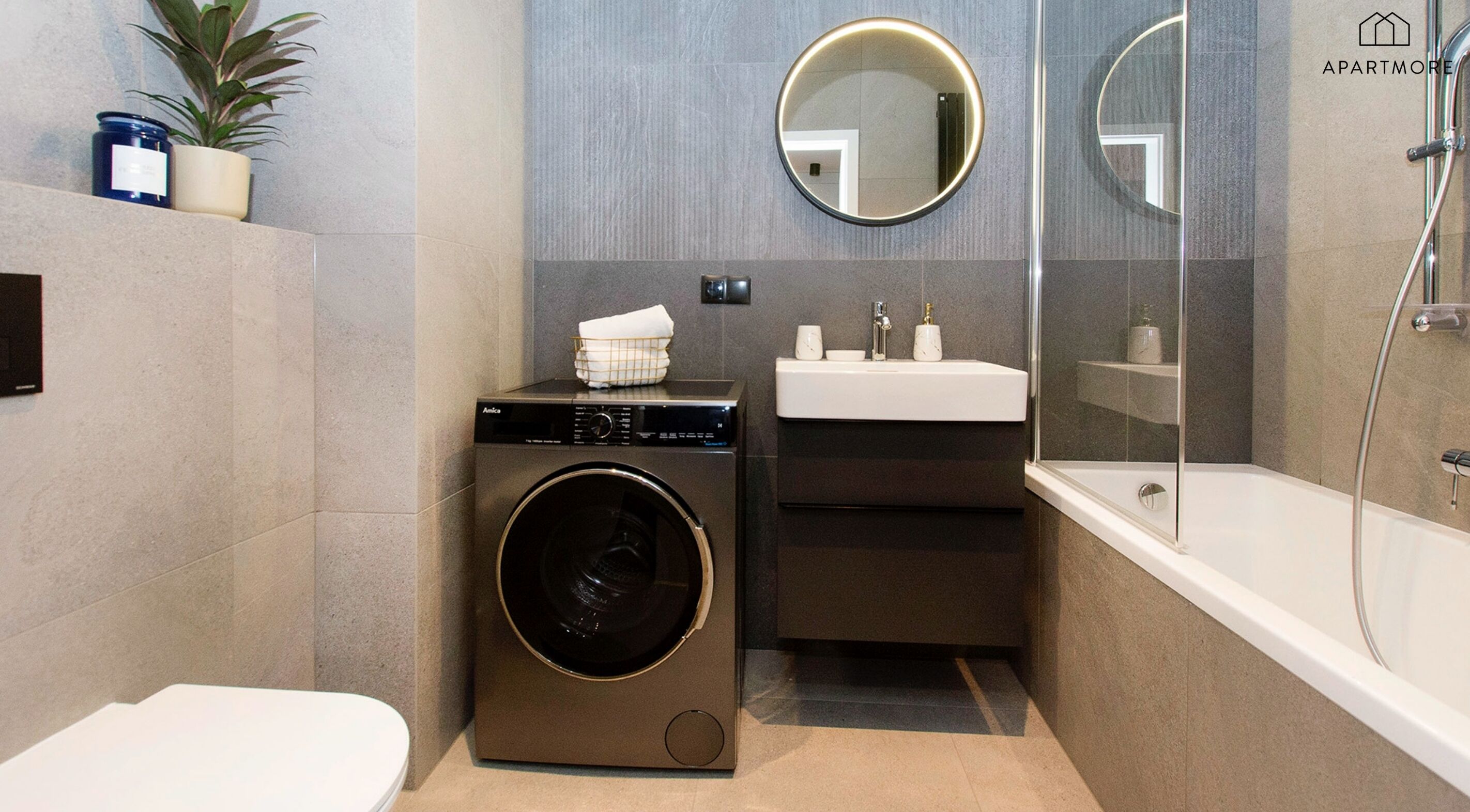 Ein kleines Badezimmer mit Waschmaschine, Waschbecken und Badewanne.