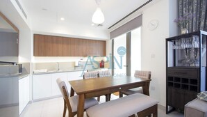 A modern kitchen with wooden cabinets, a dining table with chairs, and a built-in bench.