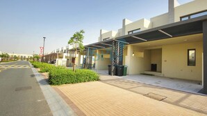 A modern building with a covered walkway, greenery, and a clear sky.