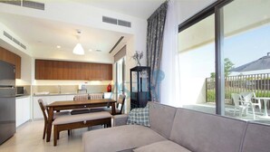 A modern living space with a sofa, dining table, and kitchen area.