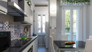 Una cucina moderna con un piano di lavoro nero, sedie bianche e un tavolo da pranzo.