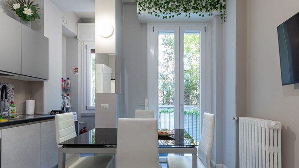 Una cucina moderna con zona pranzo, mobili bianchi e vista sull'esterno.